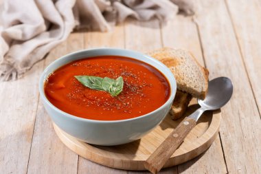 Ev yapımı domates çorbası ve ahşap masada fesleğen.