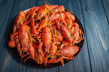 Lots of boiled crayfish. Boiled crayfish in a black plate on a black wooden background.