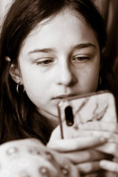 Black and white photos of a sad girl. Teenage girl shoulder looking into smartphone.