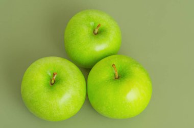 Yeşil arka planda üç olgun yeşil elma. Elmalar, meyveler. Üst görünüm