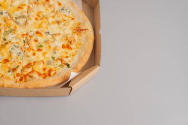 Gri arka planda karton kutuda tavuk ve pırasalı pizza. Pizza teslimatı.