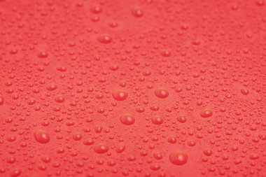 Kırmızı plastiğin üzerine su damlıyor. Kırmızı arkaplan.