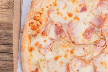 Tahta arka planda bir kutuda etli pizza.