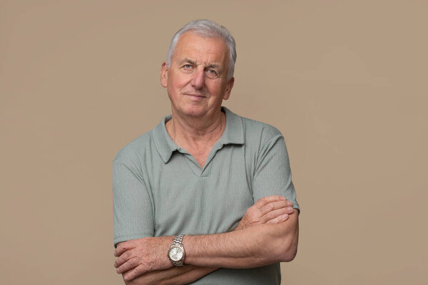 Handsome older man is posing in photo studio on brown background.