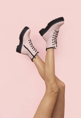 İnce kadın bacaklarında, pembe arka planda, mesajlaşmak için boş yeri olan zarif pembe çizmeler..