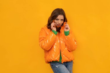 Kışlık giysiler güzel esmer tenli, uzun saçlı, izole turuncu arka planda..