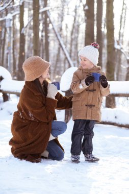 Anne ve oğlu güzel karlı orman bölgesinde kış tatili yapıyorlar..