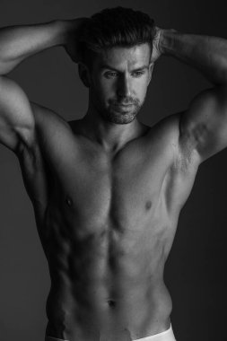 Handsome model in sensual photo session on grey background.