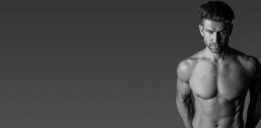 Handsome model in sensual photo session on grey background.