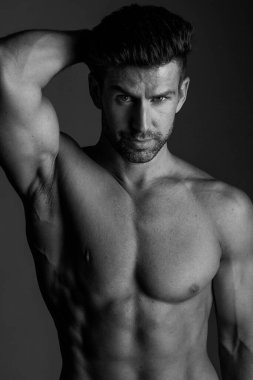 Handsome model in sensual photo session on grey background.