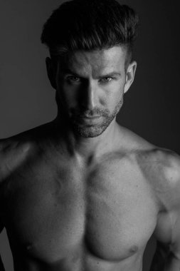 Handsome model in sensual photo session on grey background.