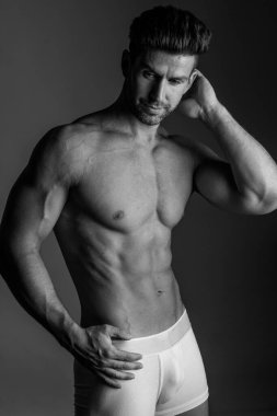 Handsome model in sensual photo session on grey background.