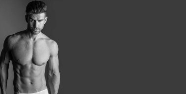 Handsome model in sensual photo session on grey background.