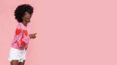 Pembe arka planda kalp süveteri giyen güzel Afrikalı kadın..