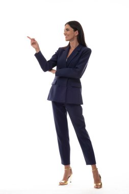 Bir fotoğraf stüdyosunun beyaz arka planında zarif bir takım elbiseli güzel bir kadın.