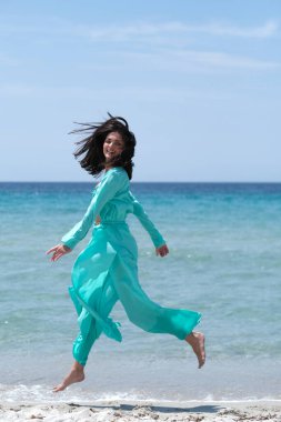 Kumsalda turkuaz elbiseli güzel bir esmer..