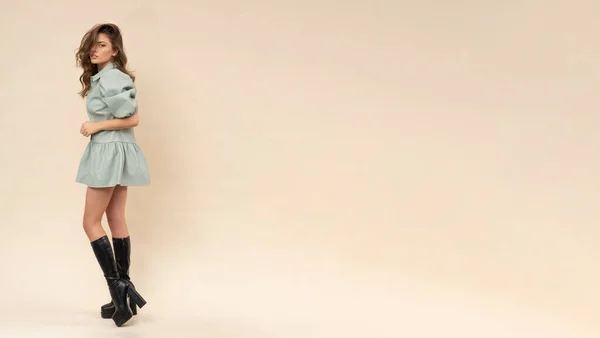 官能的な写真撮影の美しさブルネットでパステルミントドレスとブーツ上のクリーミーな背景 — ストック写真