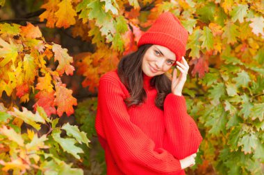 Güz manzaralı güzel esmer, kırmızı şapkalı ve atkılı..