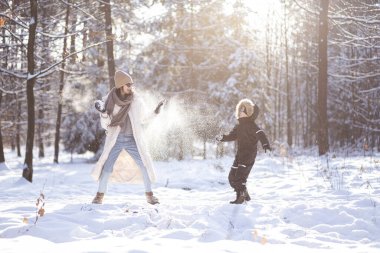Anne ve oğlu ormanda kartopu atıyorlar..