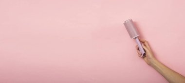 Pembe arka planda bir kadının elindeki toz silindiri..