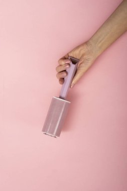 Pembe arka planda bir kadının elindeki toz silindiri..