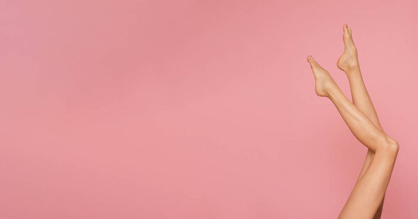 Тонкие и длинные женские ноги на розовом фоне.