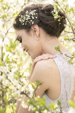 Çiçek açan ağaçlarda gelinlik içinde güzel bir esmer.