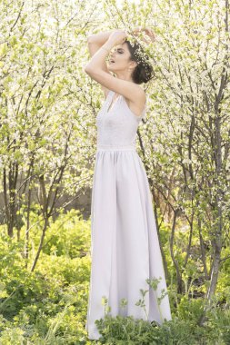 Çiçek açan ağaçlarda gelinlik içinde güzel bir esmer.