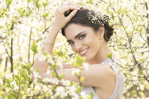 Çiçek açan ağaçlarda gelinlik içinde güzel bir esmer.