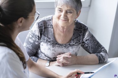 Genç bir doktor yaşlı bir hastayı muayene eder..