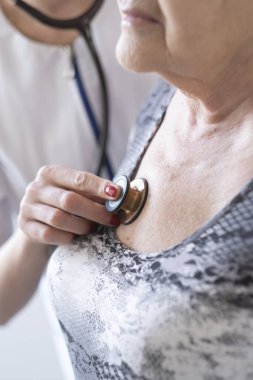 Genç bir doktor yaşlı bir hastayı muayene eder..