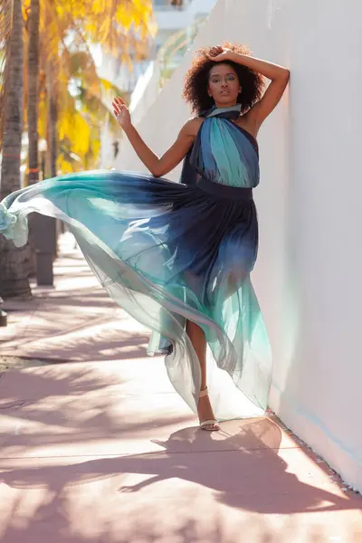 A beautiful black model in a flowing dress on the streets of Miami.