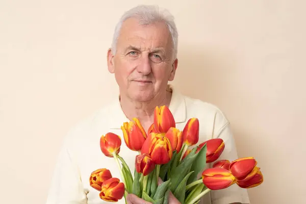 Handsome Senior Man Met Een Boeket Van Tulpen Een Crème — Stockfoto