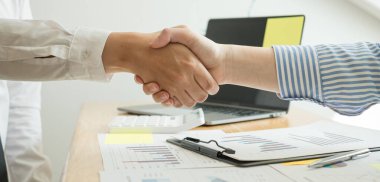 İki iş lideri çizelgeler, finansal grafikler hakkında konuşuyor. Sonuçları gösteren planlama stratejilerini analiz ediyor ve hesaplıyor. İş başarısı oluşturma süreçleri ve el sıkışıyor..