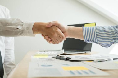 İki iş lideri çizelgeler, finansal grafikler hakkında konuşuyor. Sonuçları gösteren planlama stratejilerini analiz ediyor ve hesaplıyor. İş başarısı oluşturma süreçleri ve el sıkışıyor..