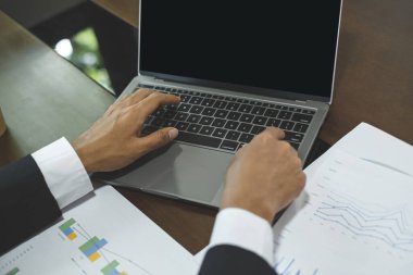 Genç Asyalı iş adamı finansal piyasa analisti masalarında oturuyor ve başarılı iş büyüme sürecini planlayan yatırımlarının sonuçlarını gösteren mali grafikleri hesaplıyor..