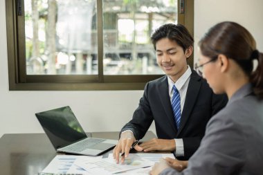 İki iş lideri çizelgeler, finansal grafikler hakkında konuşuyor. Sonuçları gösteren planlama stratejilerini analiz ediyor ve hesaplıyor. Ticari başarı oluşturma süreçlerini de..