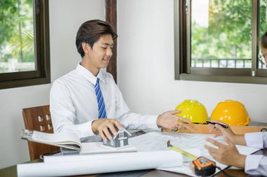 Erkek ve kadın mühendisler ve mimarlardan oluşan bir ekip, iş görüşmeleri, inşaat ve ev tasarımı projeleri hakkında tartışmalar. Ev tasarımı kavramı.