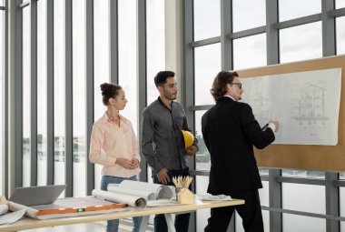 Erkek ve kadın mühendisler ve mimarlardan oluşan bir ekip, çalışma ekibi, inşaat planlarını tartışıyor ve çiziyor, baskı yapıyor, inşaat alanlarında yazıyor..