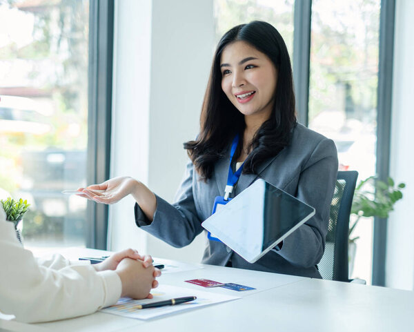 Asian business customer service representatives work and smile serve sell credit card to customers. choosing insurance plan in office.