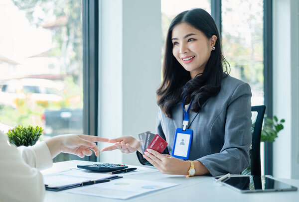 Asian business customer service representatives work and smile serve sell credit card to customers. choosing insurance plan in office.