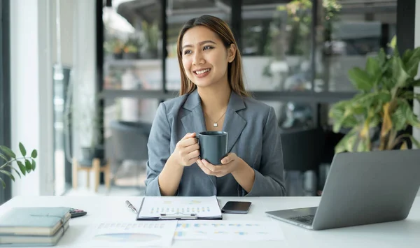 stock image Asian businesswoman smiling happily with a new morning holding a cup of coffee lightly sipping coffee professional woman in size working in the office.