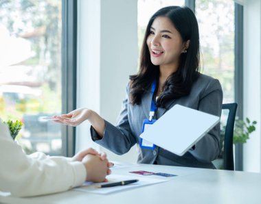 Asyalı müşteri hizmetleri temsilcileri çalışır ve gülümserler müşterilere kredi kartı satarlar. Ofisteki sigorta planını seç.