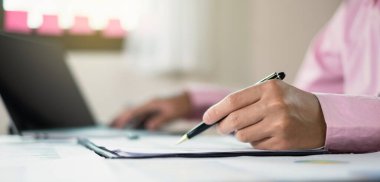İş adamı masalarında oturur ve başarılı iş büyümesi sürecini planlayan yatırımlarının sonuçlarını gösteren mali grafikleri hesaplar.