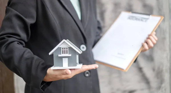 Home insurance concept and real estate. Businesswoman holding a house model working in investment about renting a house, buying a house, and home insurance.