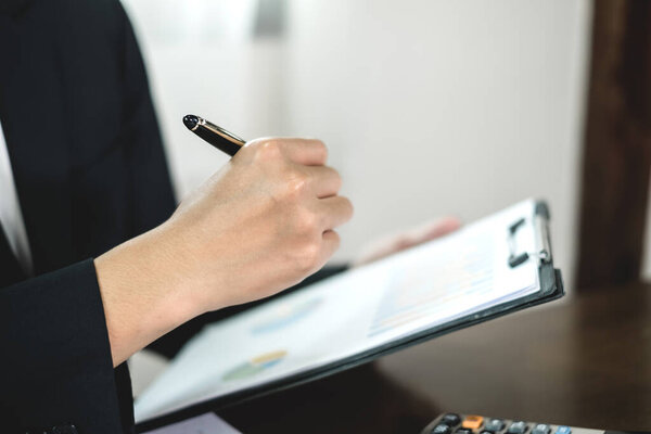 The businessman hand sits at their desks and calculates financial graphs showing the results of their investments planning the process of successful business growth.