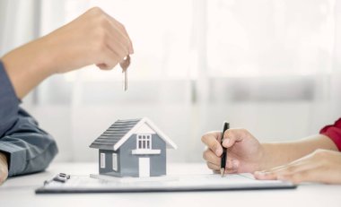 Emlak komisyoncusu imzayı attıktan sonra evin anahtarını ev kiralama ve ev sigortası konseptini satın alma anlaşmasına göre yeni sahibine teslim etti..