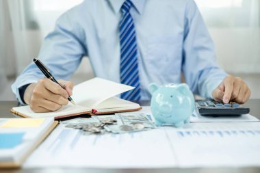 İnsan el sayımı paraları, domuz kumbarası ve hesap makinesi kullanarak emeklilik kavramları için başarılı ve ekonomik işletmeler oluşturmak için grafikler..