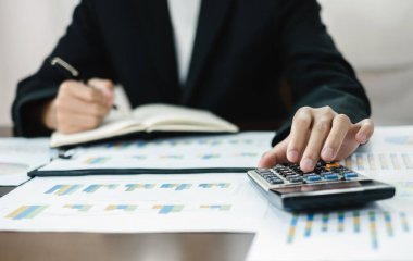 İş adamı masalarında oturur ve başarılı iş büyümesi sürecini planlayan yatırımlarının sonuçlarını gösteren mali grafikleri hesaplar.