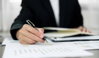 İş adamı masalarında oturur ve başarılı iş büyümesi sürecini planlayan yatırımlarının sonuçlarını gösteren mali grafikleri hesaplar.